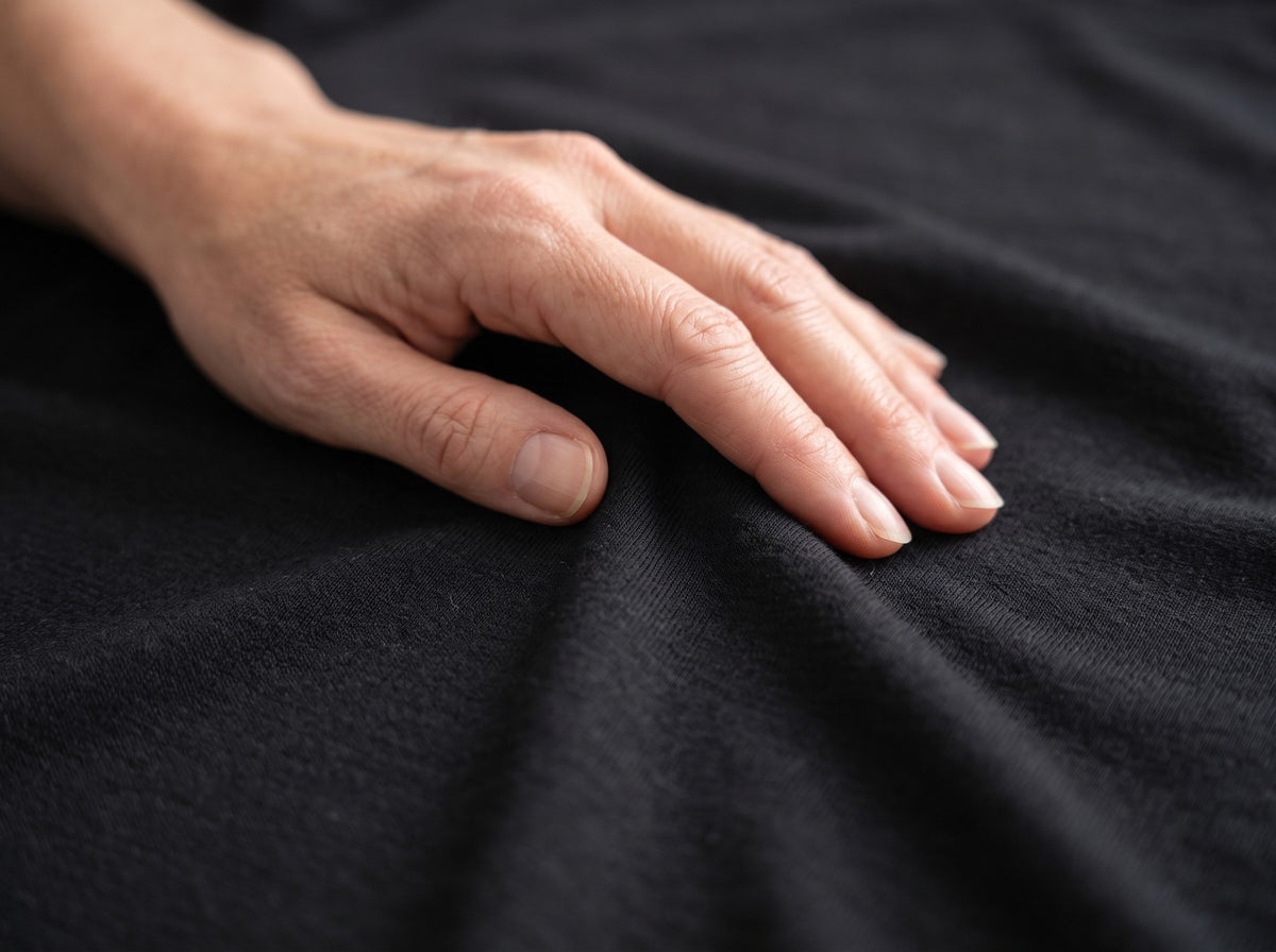 Hand gleitet über den weichen schwarzen Stoff des Merino T-Shirts Damen